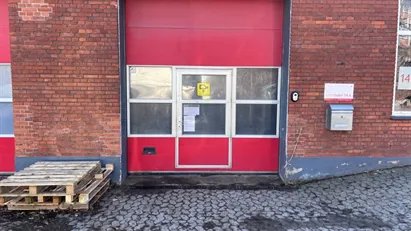 Stor hal med med ledhejseport, kontor, køkkenfaciliteter og toilet med bad.